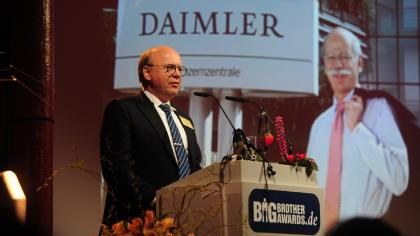 Prof. Dr. Peter Wedde am Redner.innenpult. Im Hintergrund das Daimler-Logo.