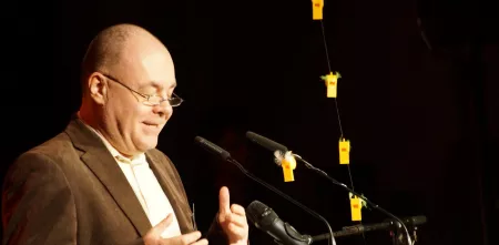 Martin Haase am Redner.innenpult während seiner Laudatio zur Kategorie Neusprech.