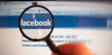 Eine Lupe, die das Facebook-Logo auf der Website vergrößert darstellt.