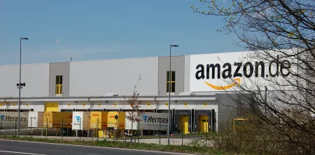 Ein Amazon-Logistikzentrum aus der Ferne. Vor dem Gebäude stehen mehrere LKWs.