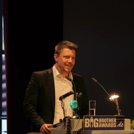 Linus Neumann am Redner.innenpult der BigBrotherAwards 2015.