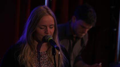 Eine Frau, die in ein Mikrofin singt.