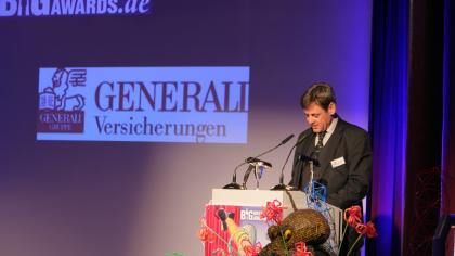 padeluun am Redner.innenpult. Im Hintergrund das Logo der Generali Versicherungen.